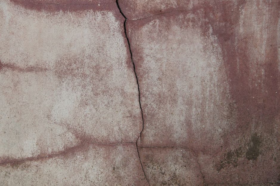 Close-up of an aged concrete wall with prominent crack, depicting texture and wear.